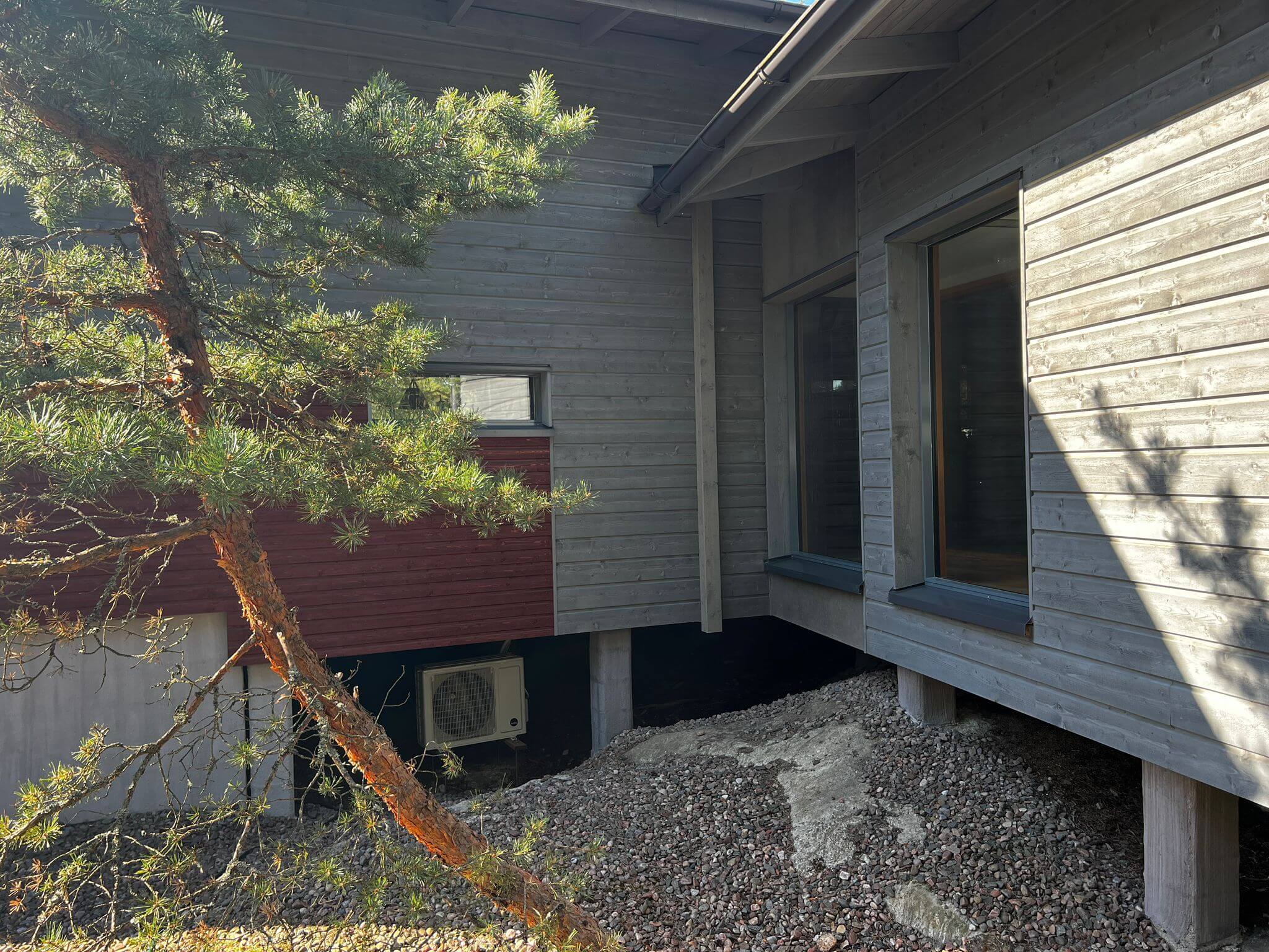 Harmaa talo, jonka alla on ilmalämpöpumppu.